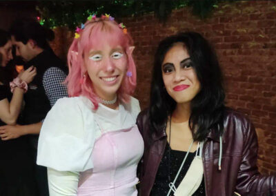Chica disfrazada de elfa con orejas puntiagudas y maquillaje rosa y blanco mira a cámara acompañada de su amiga morena que también mira a cámara