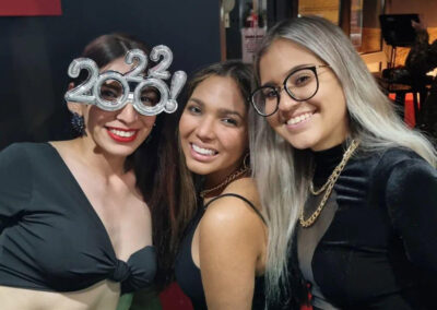 Grupo de 3 chicas sonríen felices a cámara. Una de ellas lleva unas gafas con el número 2022